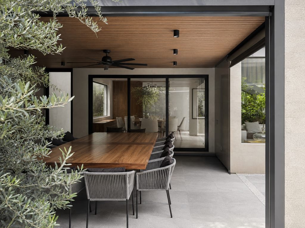 Comedor exterior bajo pérgola junto al olivo