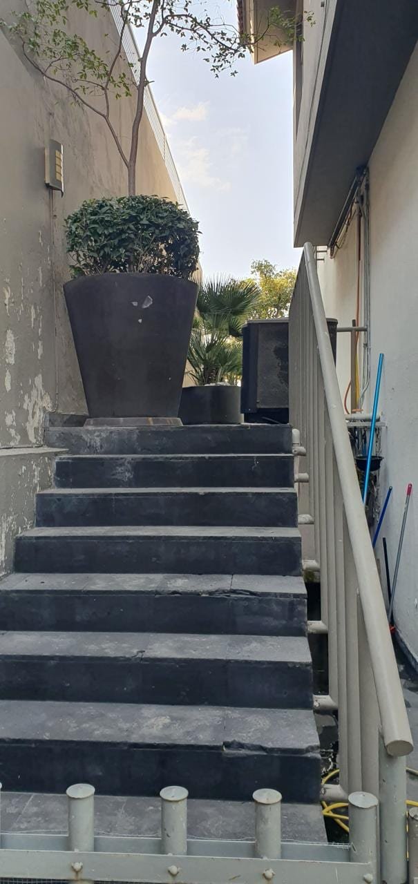 Escalera lateral de servicio antes de la obra, con el aplanado dañado