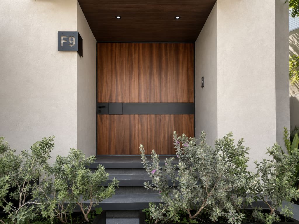 Puerta principal de madera con herrería negra y plafón de madera