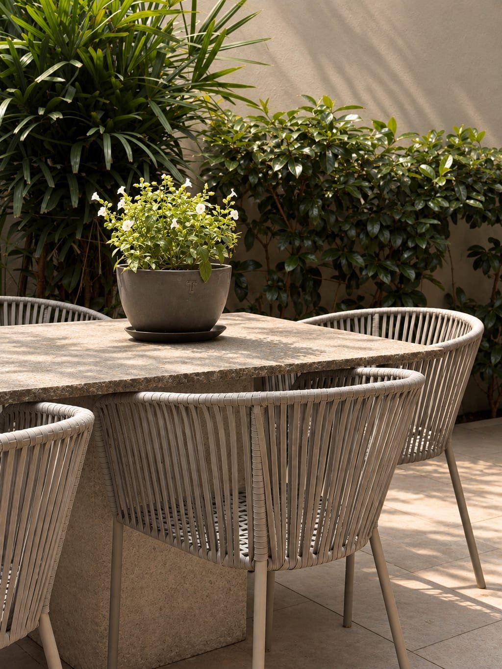 Mesa de terrazo del patio de Casa Quatro, con las sillas de tejido y una maceta